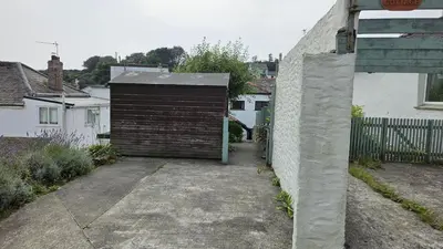 a garage with a brown door on the side of a house at Hillside Cottage in Porthscatho