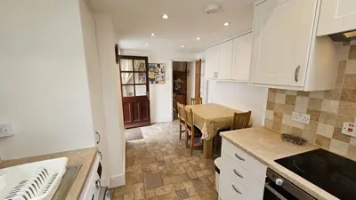 a kitchen with a table and a dining room at Hillside Cottage in Porthscatho