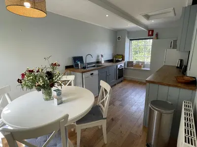 a kitchen with a white table and a table and chairs at Little Crugsillick in Veryan