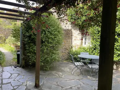 a stone patio with a table and a bench at Little Crugsillick in Veryan