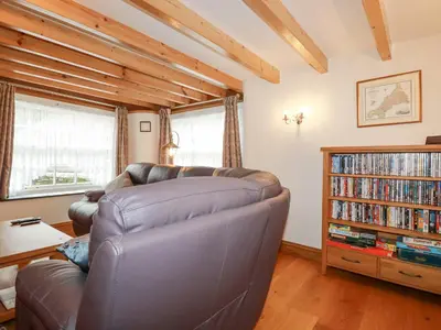 a living room with a leather couch and a bookcase at Mill Cottage in Liskeard