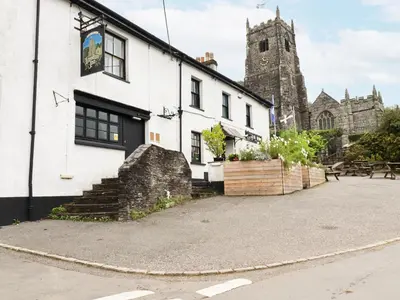 a white building with a church in the background at Mill Cottage in Liskeard