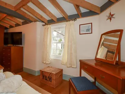 a bedroom with a mirror and a dresser and a window at Mill Cottage in Liskeard