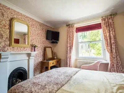 a bedroom with a bed and a fireplace and a window at The Old Mill House in Padstow