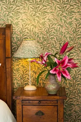 a table with a lamp and a vase with flowers on it at The Old Mill House in Padstow