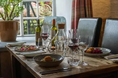 a wooden table with wine glasses and food on it at The Old Mill House in Padstow
