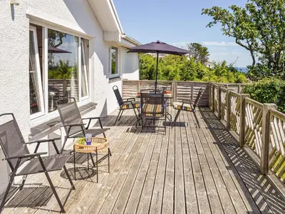 a deck with chairs and tables and an umbrella at Top Deck - Cottage in Gorran Haven