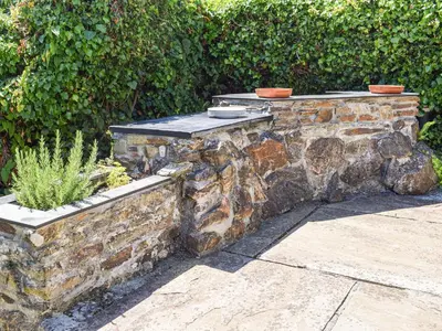 a stone retaining wall with a table on top at Top Deck - Cottage in Gorran Haven