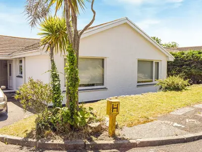a house with a palm tree in front of it at Top Deck - Cottage in Gorran Haven