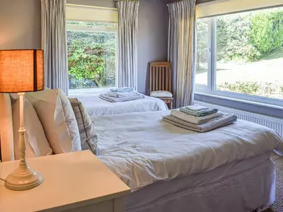 two beds in a room with a window at Top Deck - Cottage in Gorran Haven