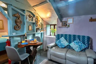 a living room with a couch and a table at Finest Retreats - Fishermans Cottage in Tintagel