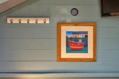 a picture of a boat on a wall with a clock at Finest Retreats - Fishermans Cottage in Tintagel