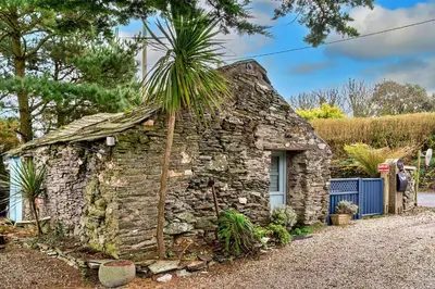 a stone house with a palm tree on top at Finest Retreats - Fishermans Cottage in Tintagel