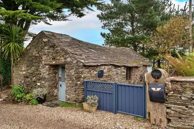 a stone house with a blue gate and a fence at Finest Retreats - Fishermans Cottage in Tintagel
