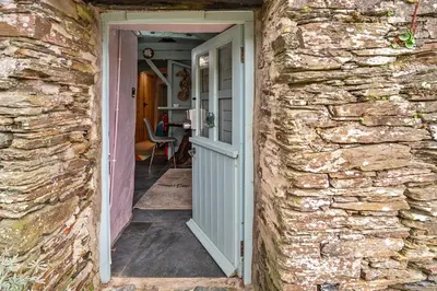 an open door into a stone house with a stone wall at Finest Retreats - Fishermans Cottage in Tintagel