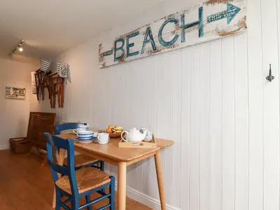 a dining room table with blue chairs and a sign that reads beach at Waves End in St Austell