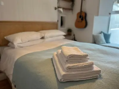 a pile of towels sitting on top of a bed at Waves End in St Austell
