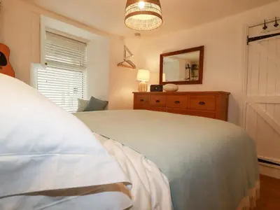 a bedroom with a bed and a dresser and a mirror at Waves End in St Austell