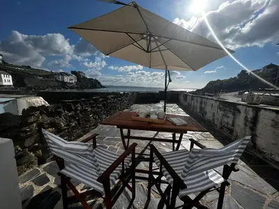 a table and chairs with an umbrella on the beach at Waves End in St Austell