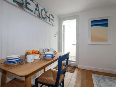 a dining room with a wooden table with blue chairs at Waves End in St Austell
