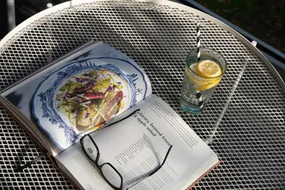 a book sitting on a table with a plate of food and a drink at Estuary Watch in St Ives