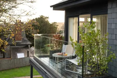 a glass balcony with a table and chairs on it at Estuary Watch in St Ives