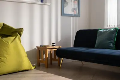 a living room with a blue couch and a table at Estuary Watch in St Ives