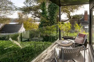 a patio with two chairs and a table on a balcony at Estuary Watch in St Ives