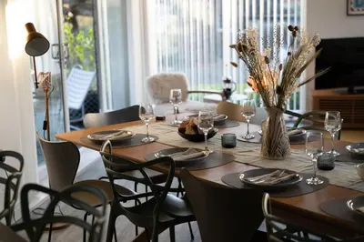 a dining room table with glasses and a vase with flowers at Estuary Watch in St Ives