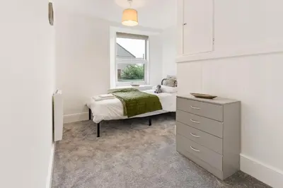 a white bedroom with a bed and a window at Delightful Family Getaway Cornwall in Mawnan Smith