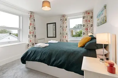 a bedroom with a bed and two windows at Delightful Family Getaway Cornwall in Mawnan Smith