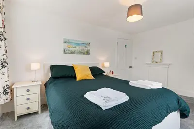 a bedroom with a green bed with two towels on it at Delightful Family Getaway Cornwall in Mawnan Smith