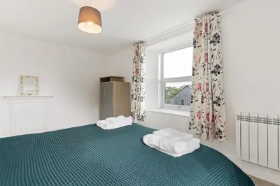 a bedroom with a green bed with towels on it at Delightful Family Getaway Cornwall in Mawnan Smith