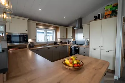 a kitchen with a bowl of fruit on a wooden table at Luxury 3 bedroom Maple View Lodge, Newquay, Cornwall in Newquay