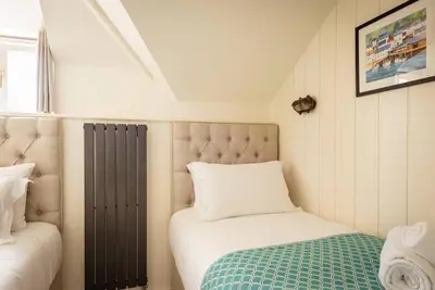 a small bedroom with a bed and a window at White House Cottage, Port Isaac Bay Holidays in Port Isaac