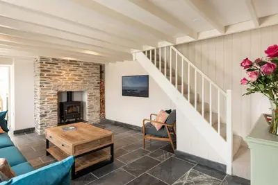 a living room with a staircase and a fireplace at White House Cottage, Port Isaac Bay Holidays in Port Isaac