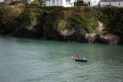 a person in a boat in a body of water at White House Cottage, Port Isaac Bay Holidays in Port Isaac