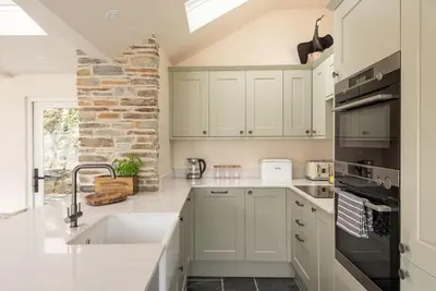 a kitchen with white cabinets and a sink at White House Cottage, Port Isaac Bay Holidays in Port Isaac