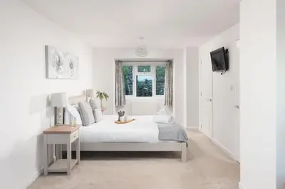 a white bedroom with a bed and a window at Chy an Mor in Coverack