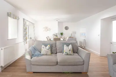 a living room with a gray couch with pillows at Chy an Mor in Coverack