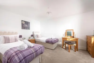 a bedroom with two beds and a dresser and a mirror at Chy an Mor in Coverack