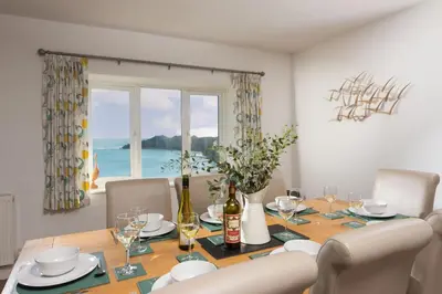 a dining room with a table with chairs and a window at Chy an Mor in Coverack