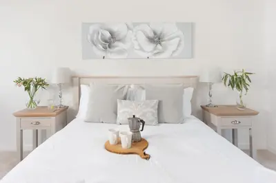 a bedroom with a white bed with two night stands at Chy an Mor in Coverack