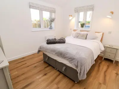 a bedroom with a bed and two windows at Puffins Rest in Penzance