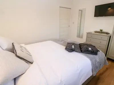 a bedroom with a white bed and a dresser at Puffins Rest in Penzance