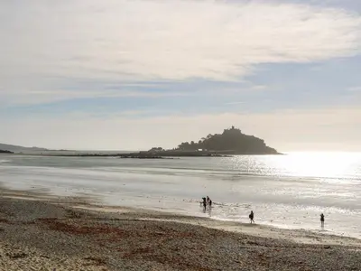 people standing on a beach with an island in the water at Puffins Rest in Penzance