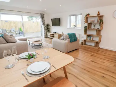 a living room with a table with plates and wine glasses at Puffins Rest in Penzance