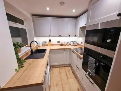 a kitchen with white cabinets and a black appliance at 1Rosemount -Marazion - Iconic view of St Michaels Mt, Sea, Beach, 2xParking, Netflix Prime in Marazion