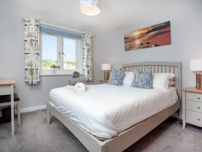 a bedroom with a bed and a desk and a window at 6 Camelside in Wadebridge