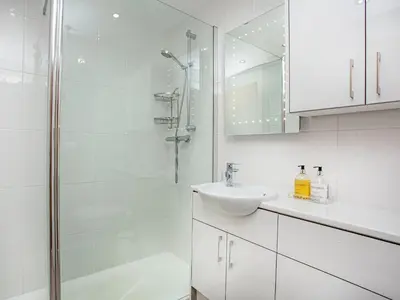 a white bathroom with a sink and a shower at 6 Camelside in Wadebridge
